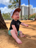 Load image into Gallery viewer, Baby on the beach under some palm trees with a beachy sun hat and a stylish respect the local shirt playing in the sand
