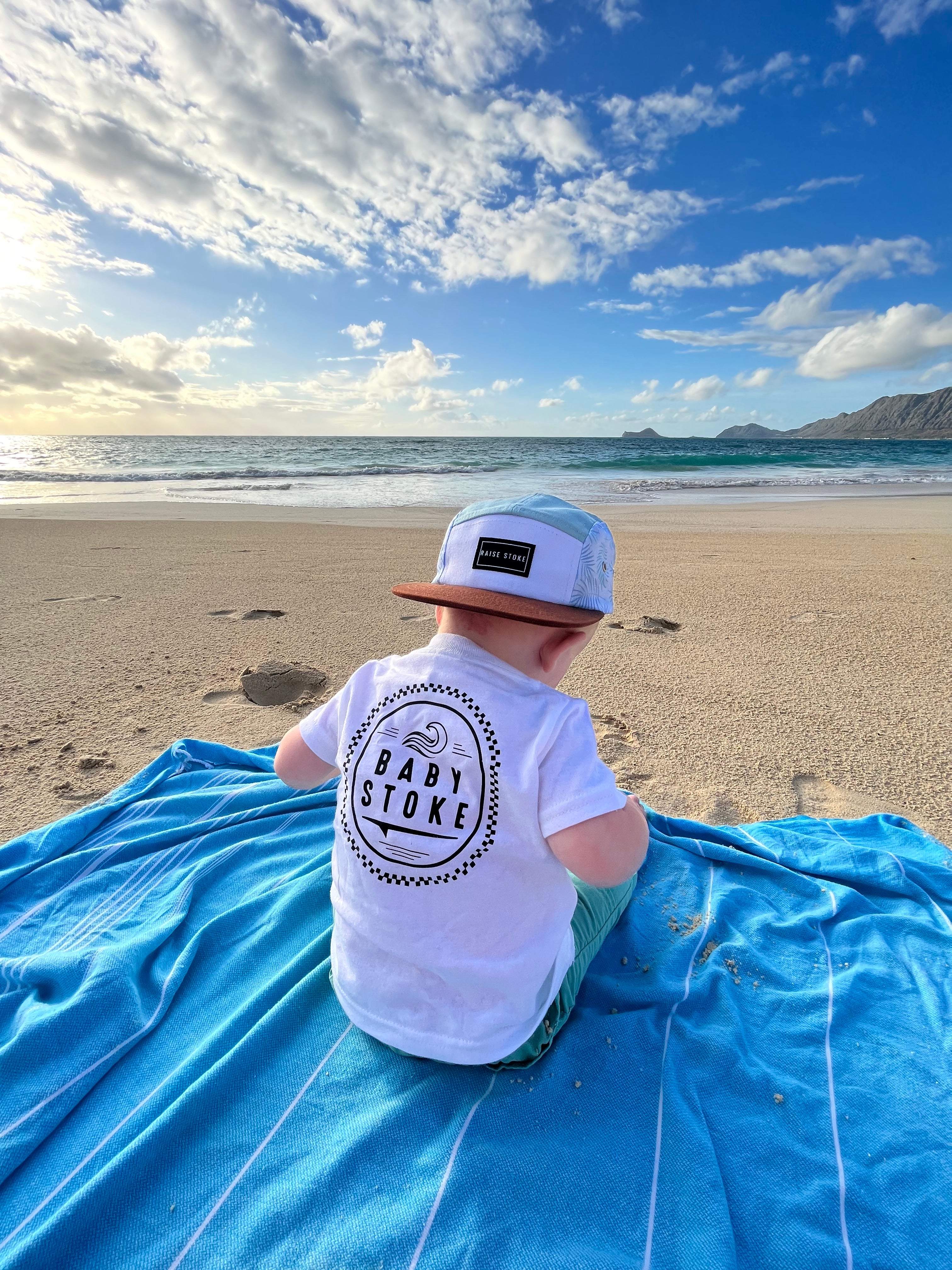 Baby on the beach with a classic t-shirt with a trendy 5 panel hat by the ocean in hawaii, beach shirt, sun shirt, trendy shirt