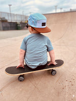 Load image into Gallery viewer, Toddler wearing a baby blue snap back flat brim hat on an adventure at the skate park with a skateboard
